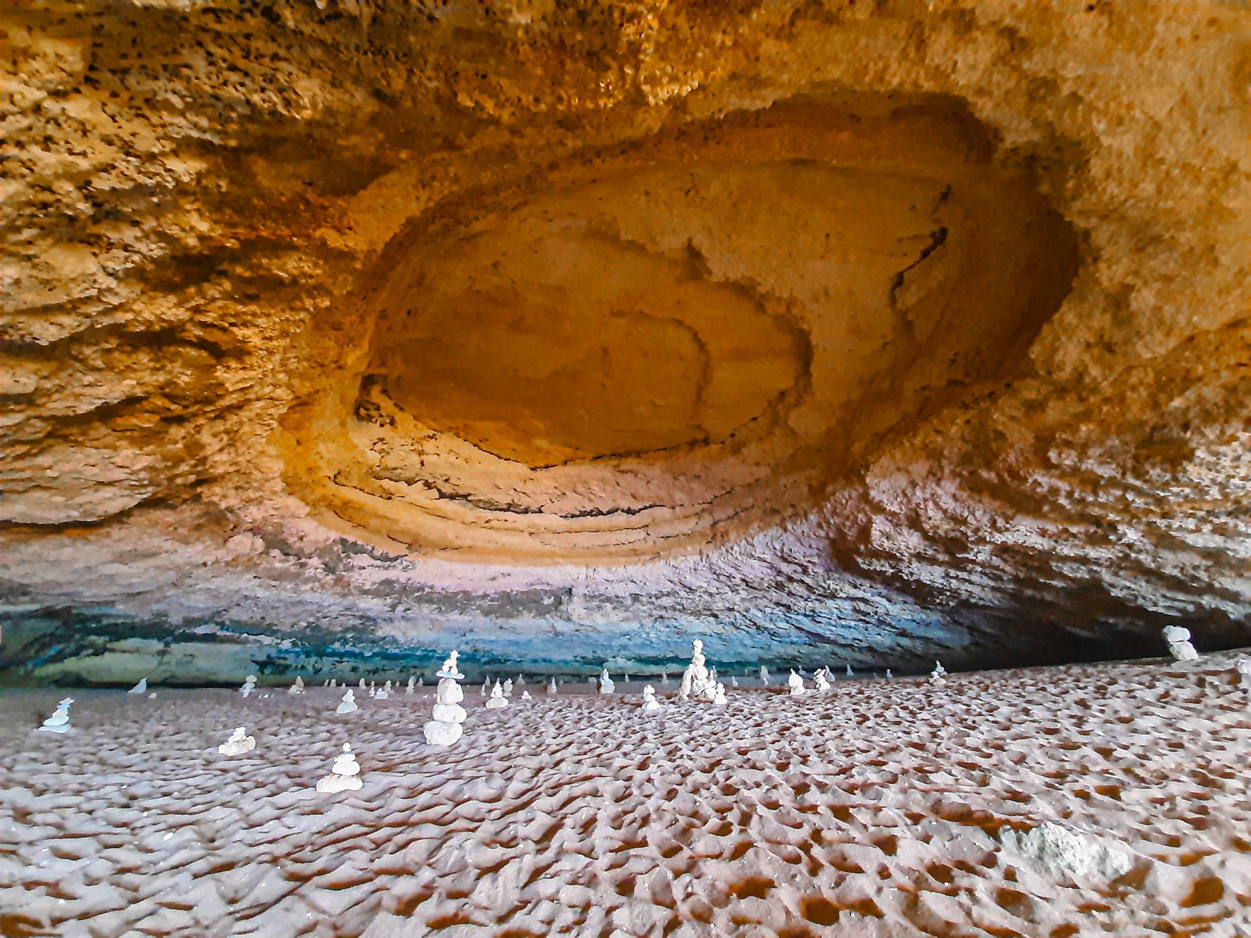 A 2021 view inside Benagil Cave, with sunlight, sand and visitors; landing on the sand is now prohibited.